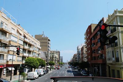 Vehicles on street amidst buildings against sky