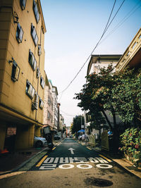 Road amidst buildings in city against sky