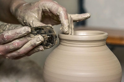Making crock crude wet close-up. man hands and tool making clay jug macro. the sculptor in workshop
