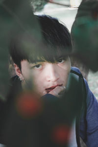 Close-up portrait of young man seen through leaves