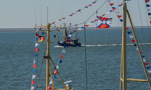 Sailboat hanging on pole by sea against sky