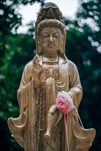 Close-up of angel statue against trees