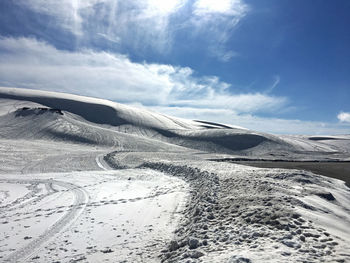 Scenic view of sand dunes against sky during winter