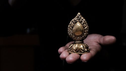 Cropped hand of man holding metallic religious object