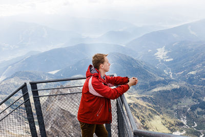 Millennial guy enjoys mountain views of alps from observation deck