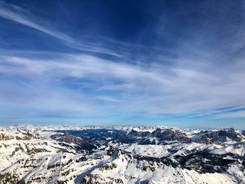 Aerial view of snowcapped mountains against blue sky