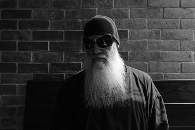 Man wearing sunglasses standing against brick wall