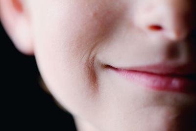 Cropped image of boy smiling against black background