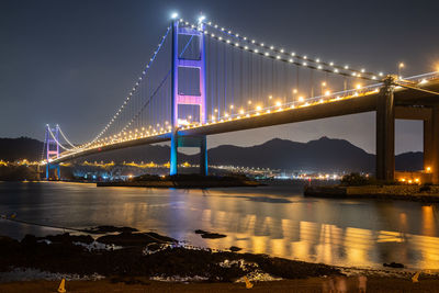 Illuminated bridge over river at night