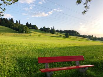 Empty bench on field against sky