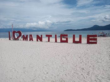 Text on beach against sky