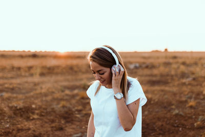 Young woman standing on field against clear sky