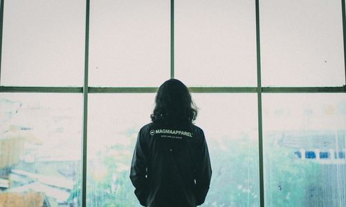 Rear view of woman looking through window