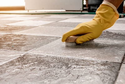 Using a wooden floor scrubber to scrub the tile floor with a floor cleaner.