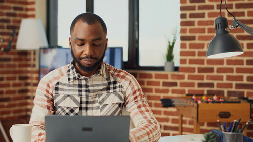 Portrait of young man using laptop at home