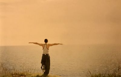 Rear view of man standing in sea against sky