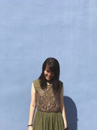 Young woman standing against wall