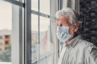 Side view of woman looking through window