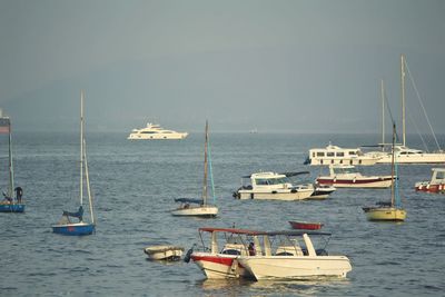 Sailboats moored in sea against sky