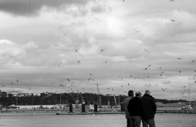 Rear view of people walking against sky