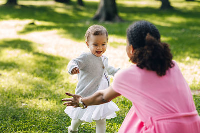 Rear view of mother and daughter on grass