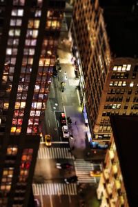 High angle view of illuminated street amidst buildings in city at night