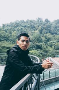 Portrait of man leaning against railing