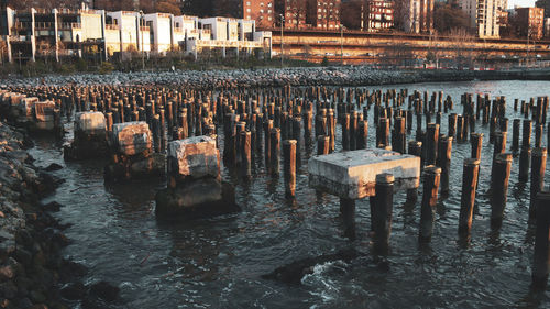 View of wooden posts in river against buildings