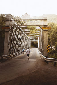 Rear view of man walking on bridge