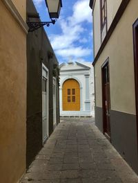 Walkway amidst buildings against sky