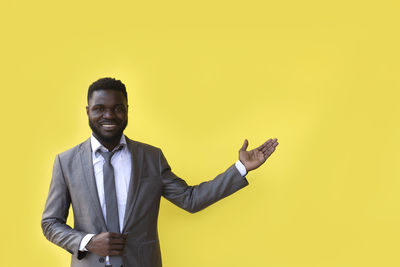 Portrait of man standing against yellow background