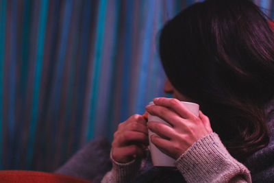 Close-up of woman relaxing while holding coffee cup at home during winter