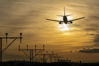 Low angle view of silhouette airplane flying against sky during sunset