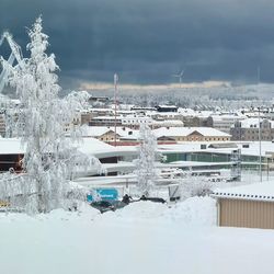 Snow covered buildings in city against sky