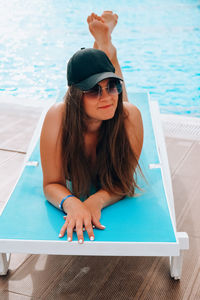 Young woman wearing sunglasses sitting on swimming pool