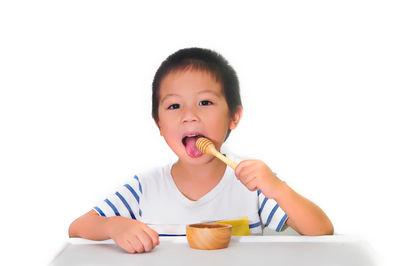 Portrait of cute boy eating food against white background