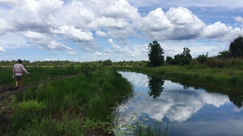 Scenic view of lake by field against sky