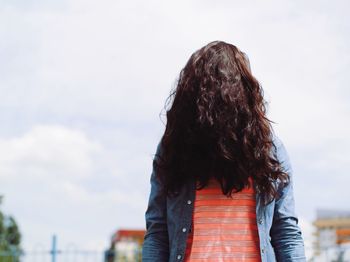 Woman with long hair standing against sky