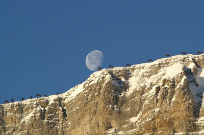 Low angle view of snow covered mountain against clear blue sky