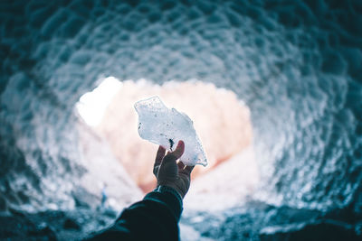 Close-up of hand holding ice on beach