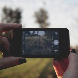 Cropped image of man photographing through smart phone