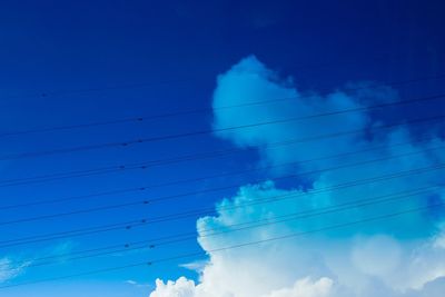 Low angle view of power lines against blue sky