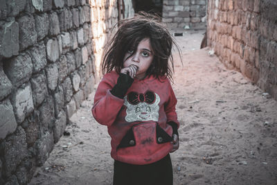 Portrait of young woman standing against wall