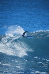 Water splashing in sea against blue sky