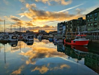 Boats moored at harbor against buildings in city