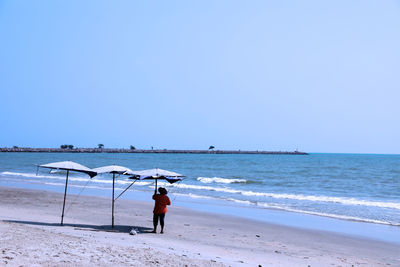 Woman on beach against clear sky