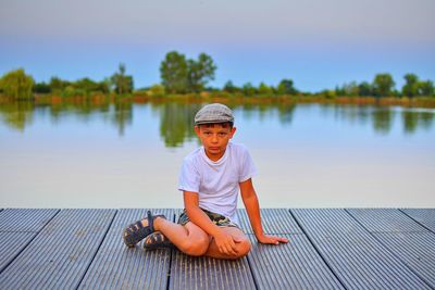 Little boy sitting on pier. elementary age boy sitting on a wooden pier. summer and childhood