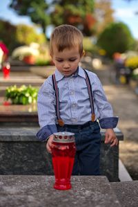 Little toddler holding a candle on the grave