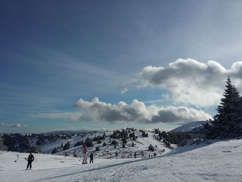 People skiing on snow against sky