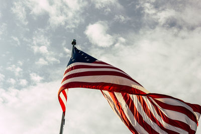 Low angle view of american flag waving against sky